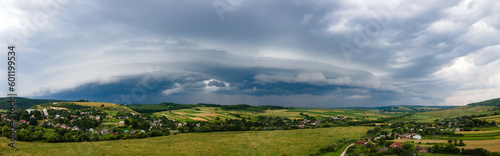 Fotografiet Landscape of dark clouds forming on stormy sky during thunderstorm over rural ar