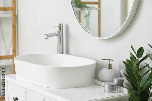Sink and different cosmetic products in light bathroom
