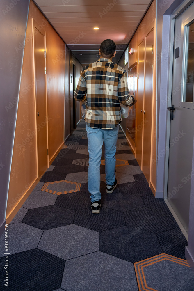 Young man in a plaid shirt in a hotel corridor