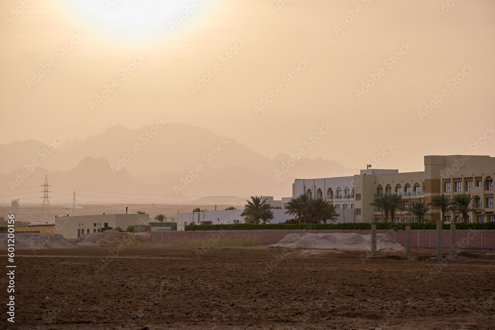 Sunset landscape with remote hotel complex against dark mountain peaks in egyptian desert Sunset landscape with remote hotel complex against dark mountain peaks in egyptian desert