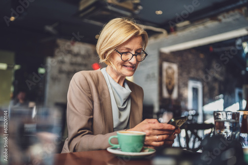 Mature Blonde causacian Woman use Smartphone at Cafe while sit alone