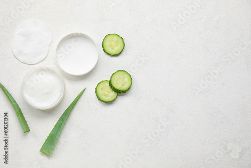 Composition with jar of natural cream, cotton pads, aloe leaves and cucumber on light background