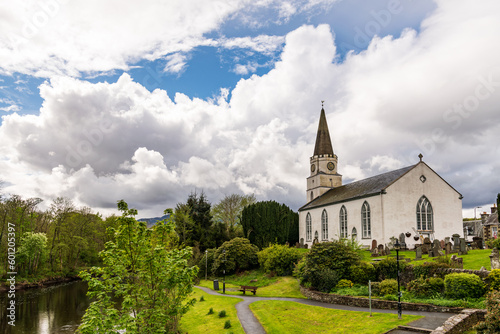 The river earn flowing past the white church in the perthshire (scotland) village of comrie with green wooded banks, dramatic white clouds and reflections in the water. photo