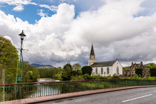 The river earn flowing past the white churh in the perthshire (scotland) village of comrie with green wooded banks, dramatic white clouds and reflections in the water. photo