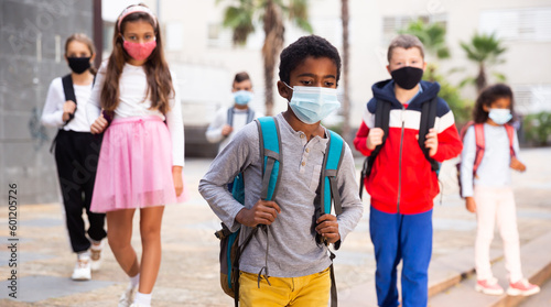African american tween schoolboy in protective mask with backpacks going to school lessons on fall day. Back school concept during pandemic