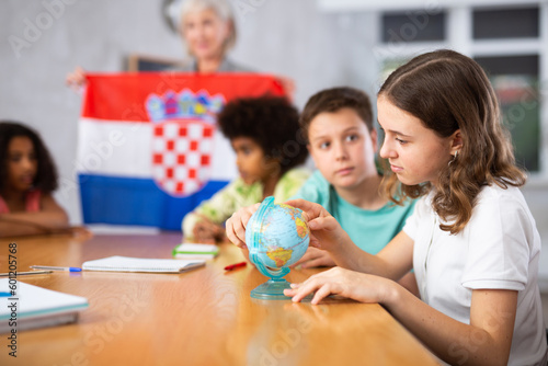 Ten-year-old schoolgirl is studying the history of Croatia in lesson and an attentively is looking for her on the globe