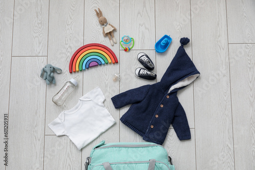 Stylish clothes and toys for baby on light wooden background
