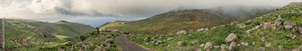 Huge panorama landscape of beautiful sunset over road on countryside full of mountains, green fresh grass, rocks and ocean in tenerife, canarias, spain