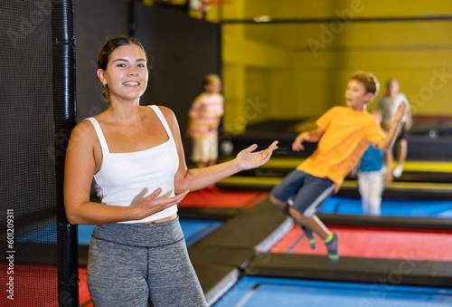 Portrait of cheerful young female in sportswear posing and smiling at camera on colorful trampoline at game club
