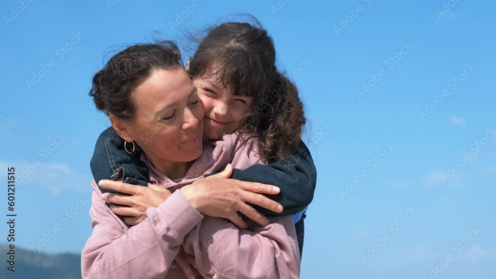 Kid hug mum. A smiling little girl hugs her mother from back with joy on the shore. A concept of family time during summer time. Kid hug mum. A smiling little girl hugs her mother from back with joy on the shore. A concept of family time during summer time.