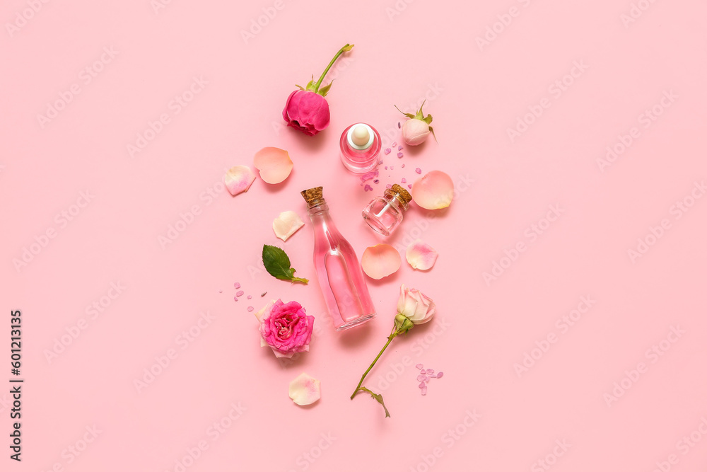 Bottles of cosmetic oil with rose extract and flowers on pink background Bottles of cosmetic oil with rose extract and flowers on pink background