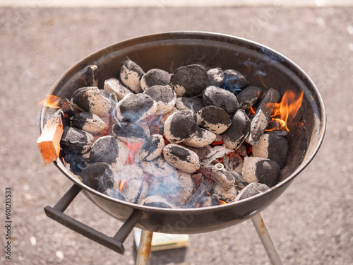 Starting up garden barbeque. Heating up charcoal stage. Burning coal. Summer time activity, Food preparation in a park or backyard.