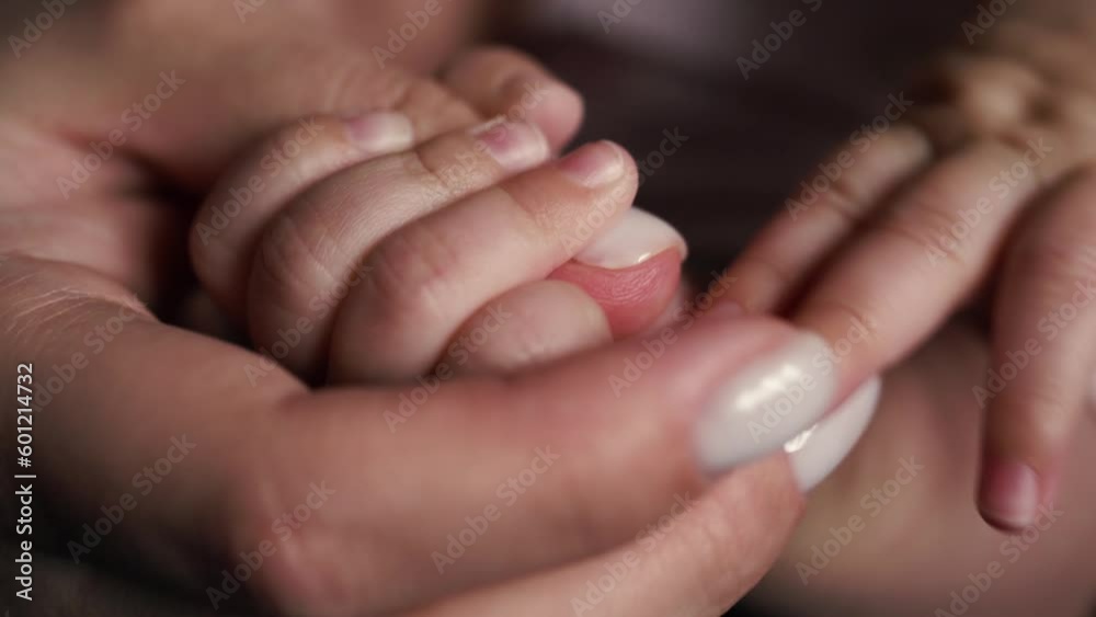 The tender hands of a mother with white manicure hold her daughter's little fingers, her child with nails. Day. Static camera The tender hands of a mother with white manicure hold her daughter's little fingers, her child with nails. Day. Static camera