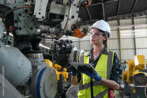 Mechanical engineers with robotic welder., Programming development technology work. Female industrial engineer working at automated AI robotic production factory..