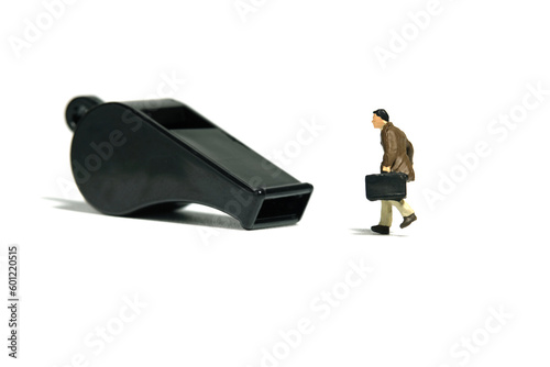Miniature people toy figure photography. Whistle blower concept illustration. A businessman running toward black whistle, isolated on white background