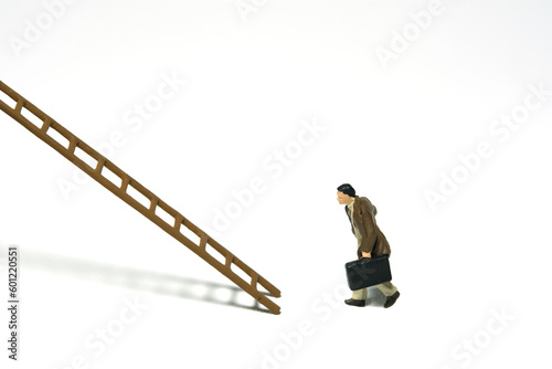 Miniature people toy figure photography. Success career stair concept illustration. A businessman running toward wooden ladder, isolated on white background