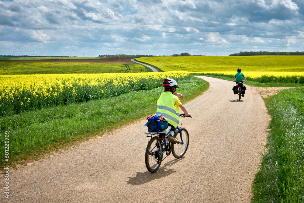 Obraz premium Aventures en famille avec les voyageurs à vélo à travers les champs de colza jaune en France