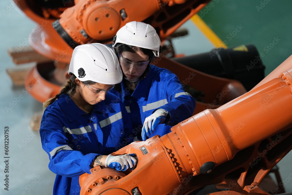 Robotics engineer working on maintenance of robotic arm in factory warehouse. Business technology. Robotics engineer working on maintenance of robotic arm in factory warehouse. Business technology.