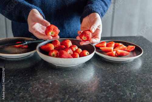 strawberries cutting. Hands cut fresh strawberries and put in a plate. Preparing strawberries for serving. 