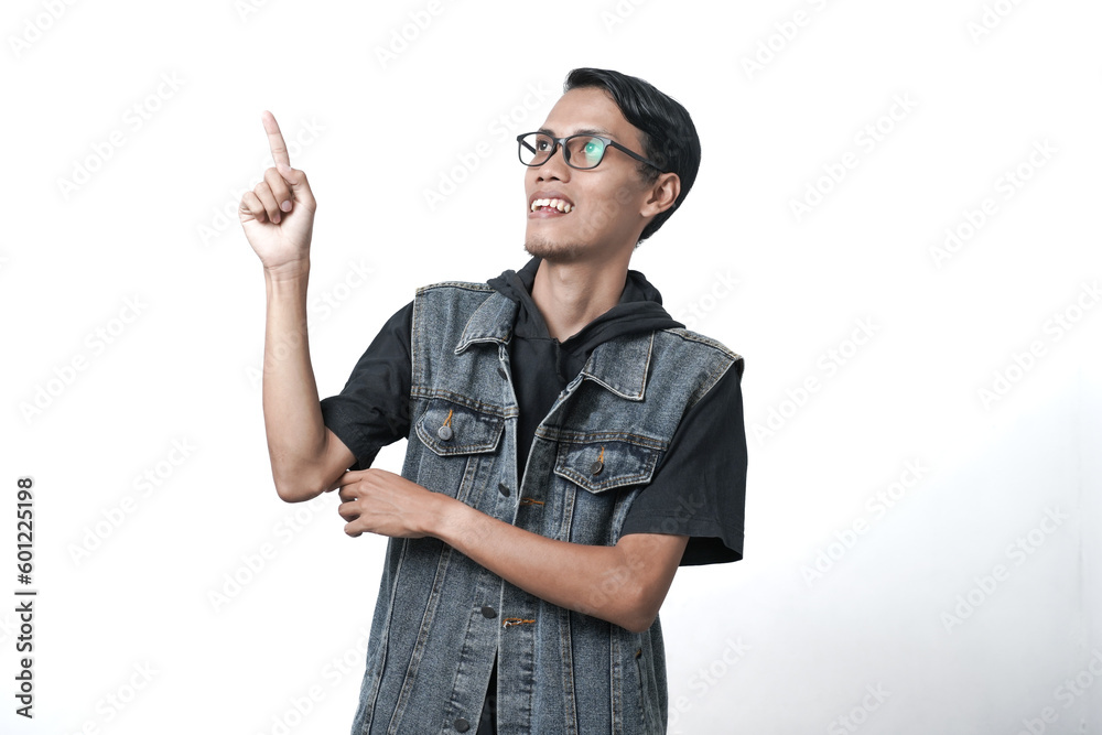 Asian man wearing sleeveless blue jean jacket, pointing above empty space. Isolated white background Asian man wearing sleeveless blue jean jacket, pointing above empty space. Isolated white background