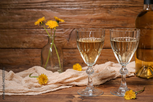 Bottle and glasses of dandelion wine on wooden table