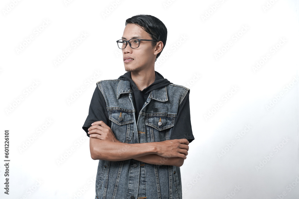Asian man wearing sleeveless blue jean jacket crossed arms positive expression. Isolated white background Asian man wearing sleeveless blue jean jacket crossed arms positive expression. Isolated white background