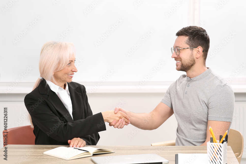 Happy woman shaking hands with man at wooden table in office. Manager conducting job interview with applicant Happy woman shaking hands with man at wooden table in office. Manager conducting job interview with applicant