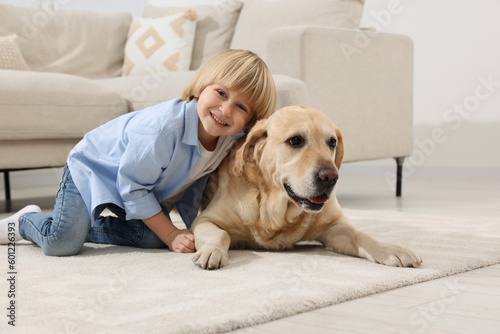 Cute little child with Golden Retriever on floor at home. Adorable pet