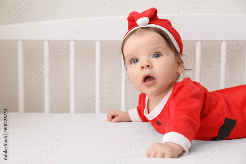 Cute baby wearing festive Christmas costume in crib. Space for text