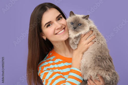 Happy woman with her cute cat on violet background