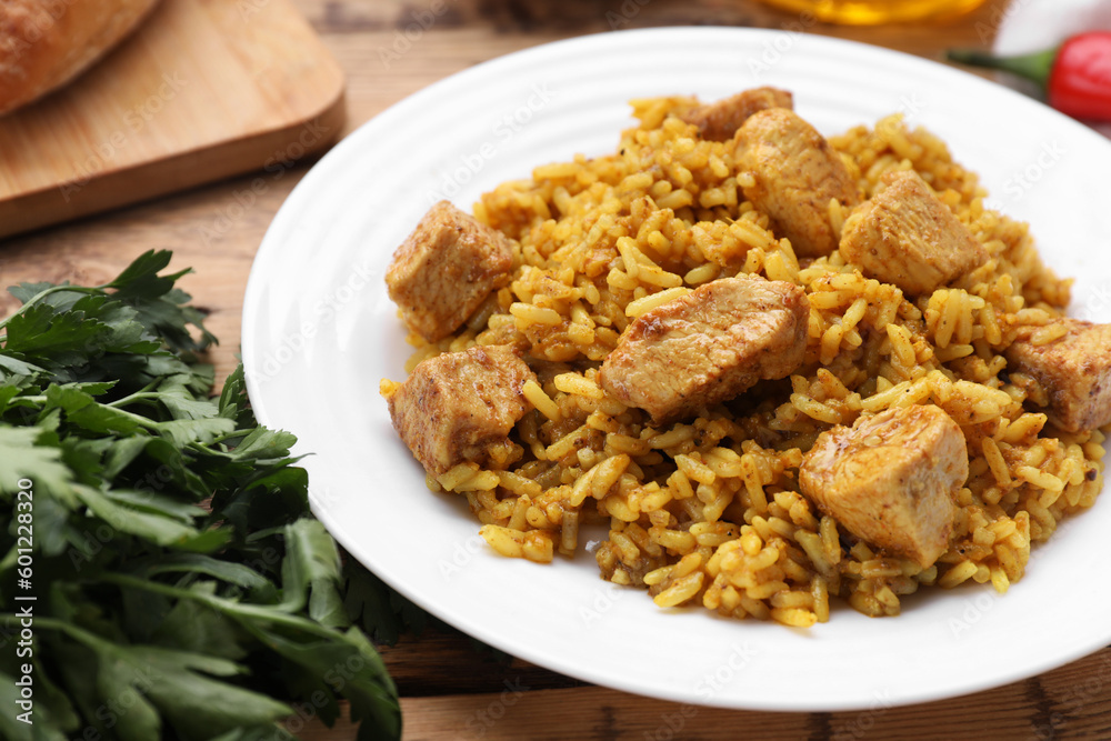 Delicious rice with chicken served on wooden table, closeup Delicious rice with chicken served on wooden table, closeup