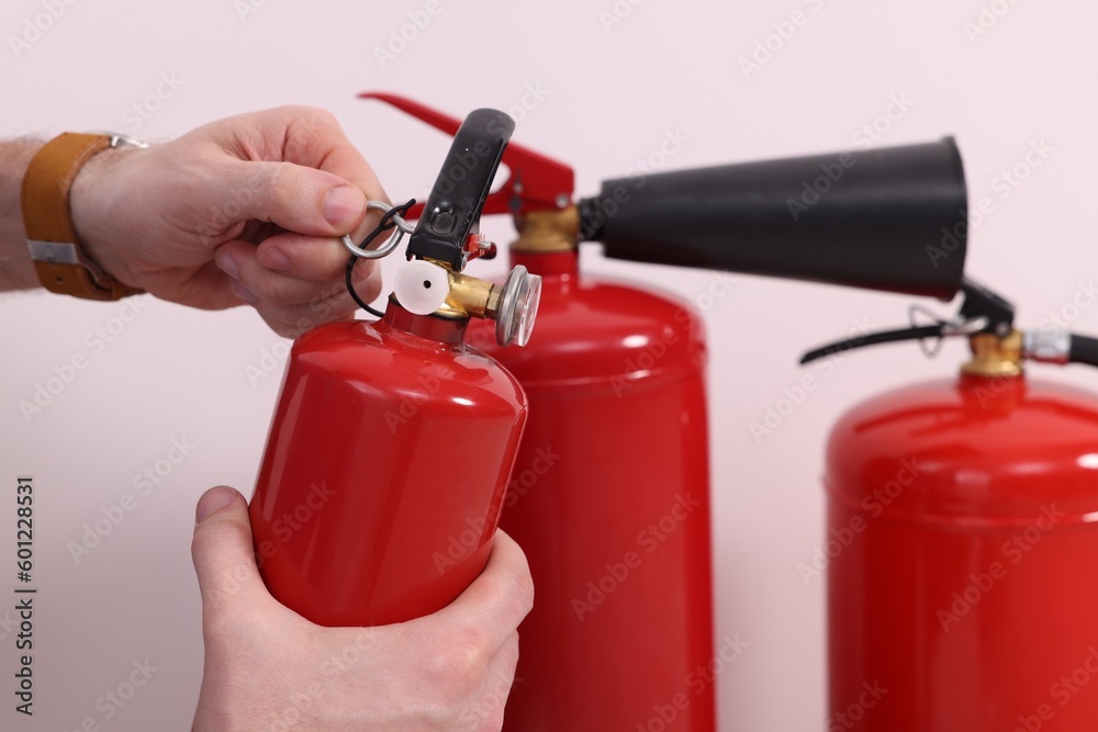 Naklejka premium Man checking quality of fire extinguishers indoors, closeup