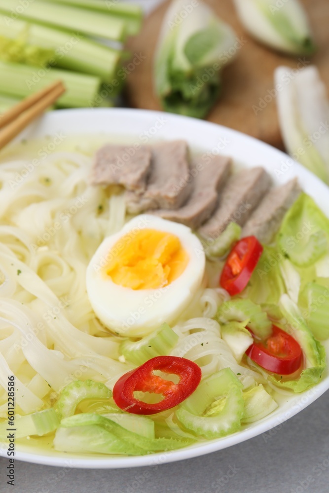 Bowl of delicious rice noodle soup with meat and egg on light grey table, closeup Bowl of delicious rice noodle soup with meat and egg on light grey table, closeup