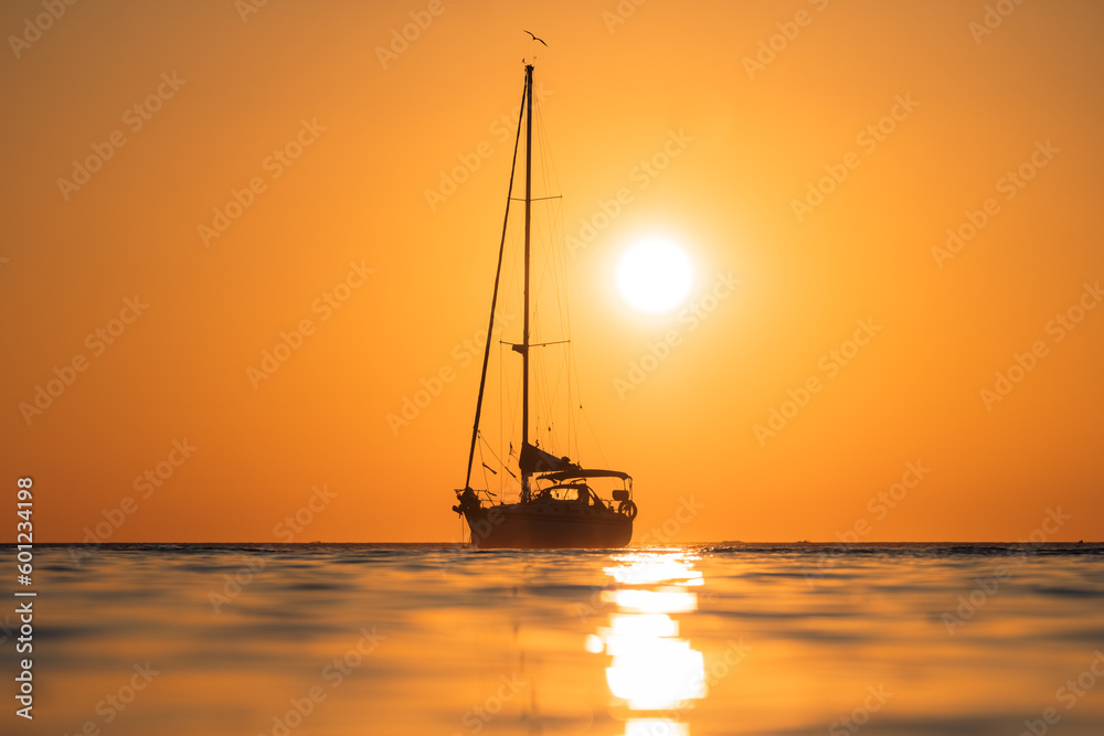 Close backlit shot of a ship sailing in the middle of the sea during sunset