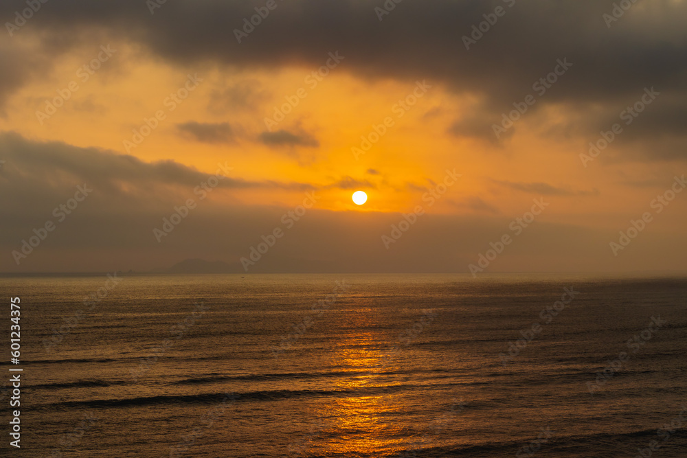Amazing sunset over the beach of Barranco, Lima - Peru. The sun setting through the clouds with a great view of the sea. Vacation, nature, ecosystem.