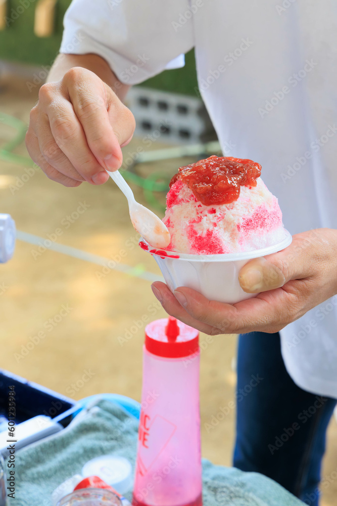 夏場イベントでイチゴ味のかき氷を作る男性