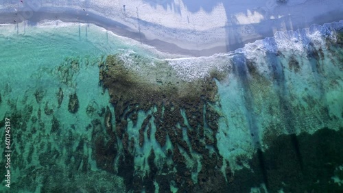 A rising aerial shot of the beautiful rocks at North Cottesloe Beach, Perth Western Australia. People can be seen walking on their morning beach walk photo