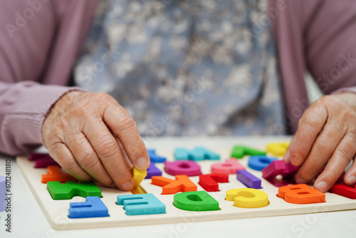 Asian elderly woman playing puzzles game to practice brain training for dementia prevention, Alzheimer disease.