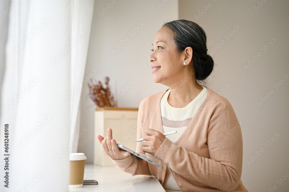 Charming senior Asian woman sits in a coffee shop, daydreaming about her retirement. Charming senior Asian woman sits in a coffee shop, daydreaming about her retirement.