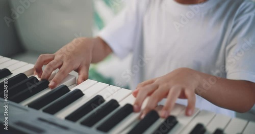 Close-up hand of Creative asian boy with artistic skills taking music lessons online during a video call and playing the piano at home. Music, hobby and lifestyle concepts.