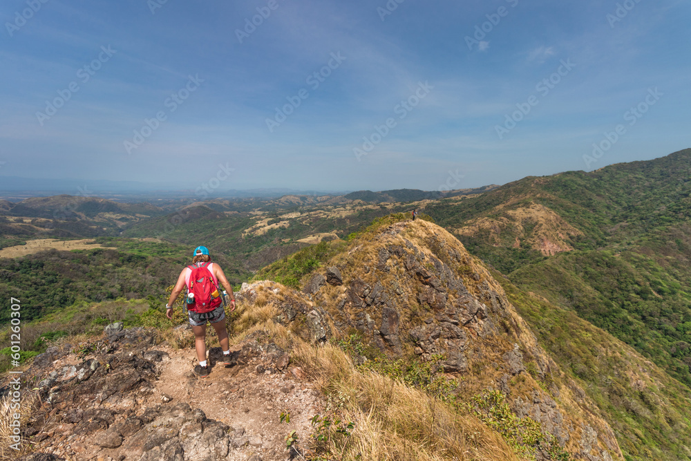 female hiker walking along the edge of a hill on a hot sunny day in the province of Puntarenas in Costa Rica