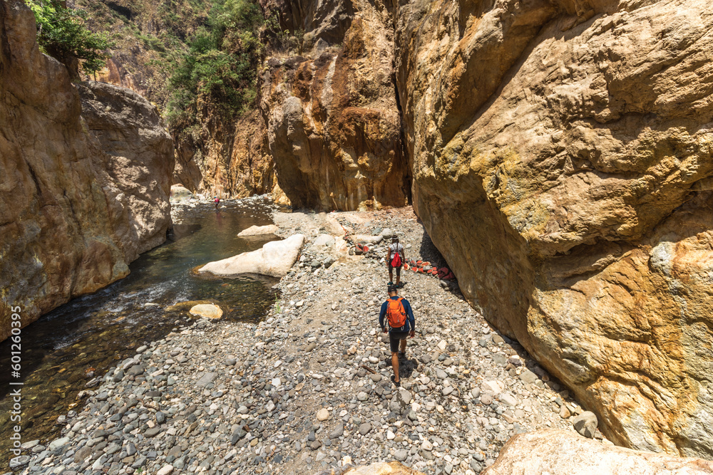 group of hikers walking through a rocky canyon and riverbed on a hot sunny day in the province of Puntarenas in Costa Rica