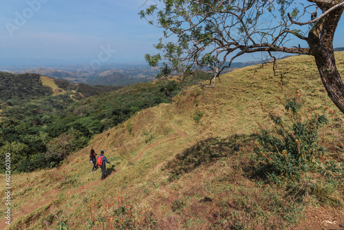 couple of hikers walking on a path surrounded by nature and countryside in Puntarenas of Costa Rica