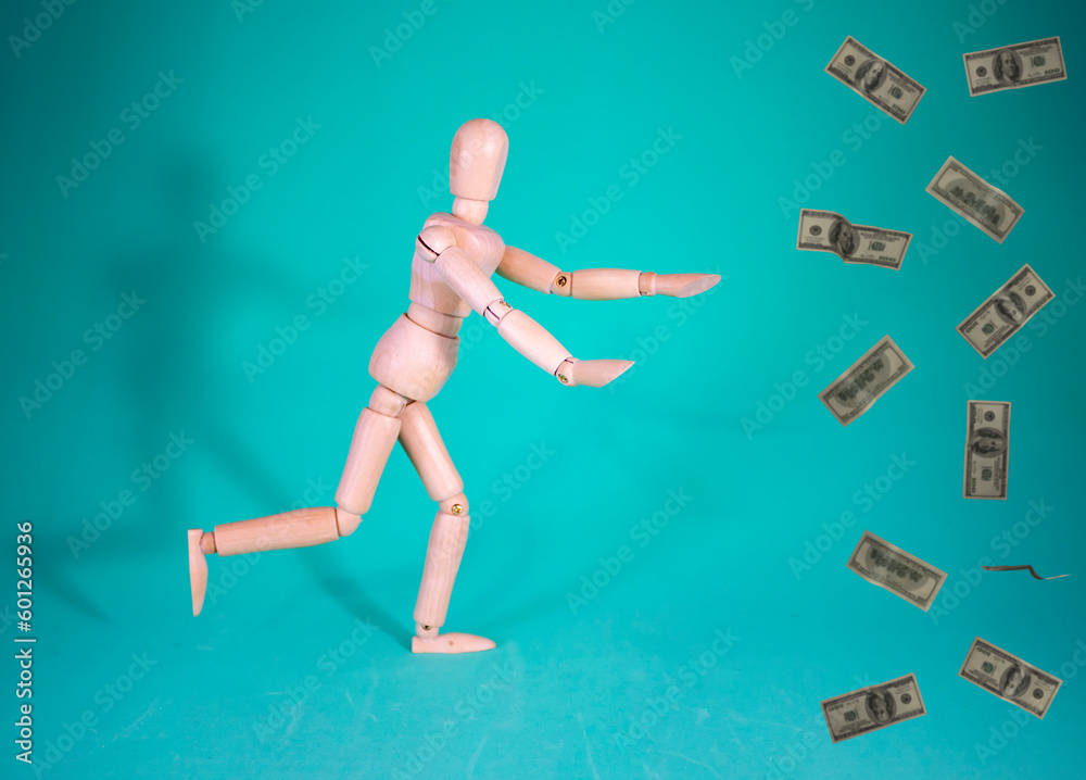 Wood Man and Money. Cheerful Wooden Doll on a Blue Background with Outstretched Arms Chasing Money and Wealth and with Empty Space for Text. Wood Man and Money. Cheerful Wooden Doll on a Blue Background with Outstretched Arms Chasing Money and Wealth and with Empty Space for Text.