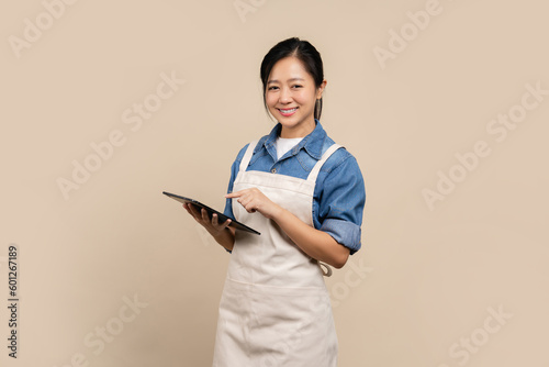 Small business owner of young Asian woman wearing aprons holding a tablet. Looking at the camera.