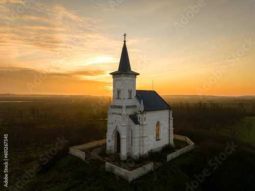 Small white chapel in alone in the fileds with scenic sunrise colored sky.