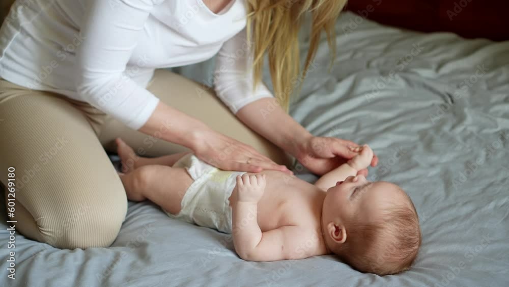 Mom massages the baby tummy with her hand. Children massage. Nanny, maternity leave,colic, massage therapist concept Mom massages the baby tummy with her hand. Children massage. Nanny, maternity leave,colic, massage therapist concept