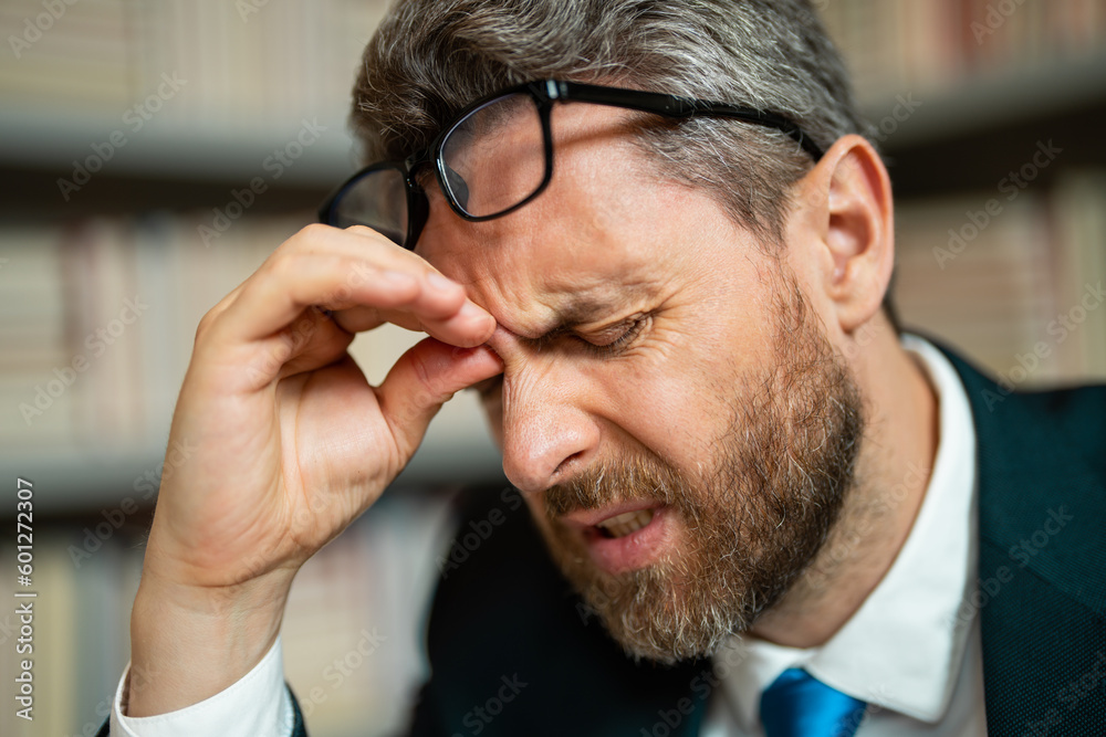 Obraz premium Close up face of stressed man with headache migraine. Overworked man feeling migraine head strain. Tired bored man has office syndrome.