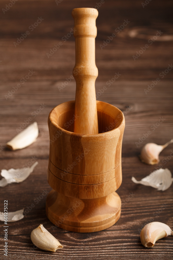 Close up of a wooden mortar and pestle and garlic cloves around. wooden table . Copy space