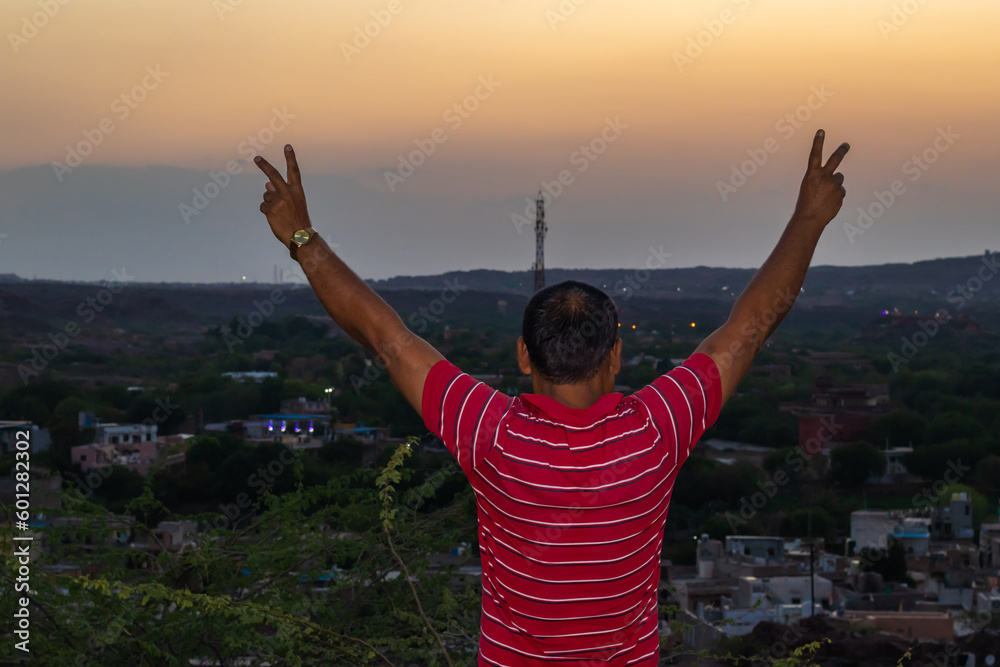 man standing on mountain top with city house construction and mountain background at evening man standing on mountain top with city house construction and mountain background at evening